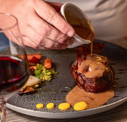 Mesa con solomillo, papas y bebidas desde otro ángulo en Hi-Life Steak House con vistas al océano